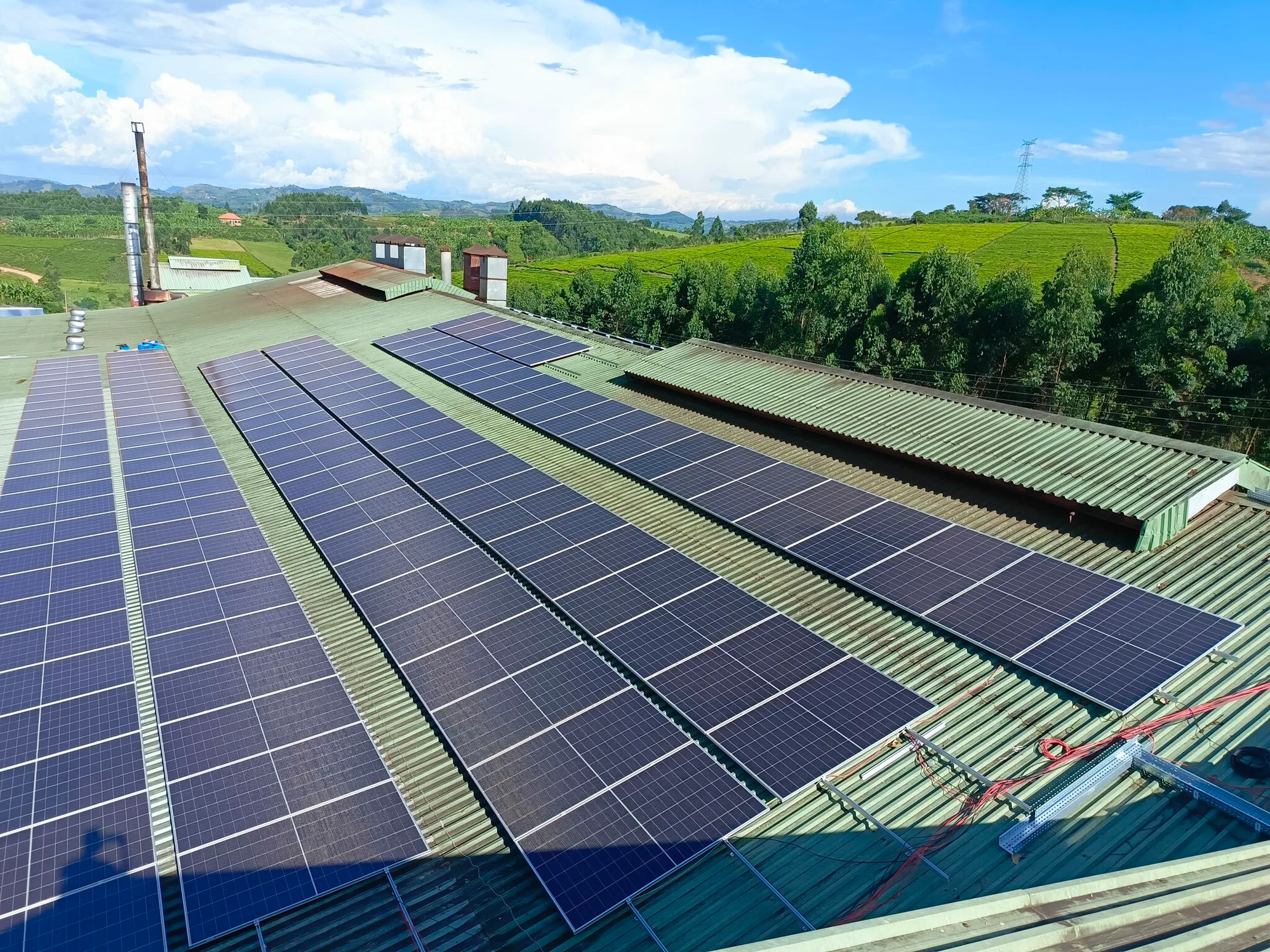 Rooftop solar array on an industrial building surrounded by green hills
