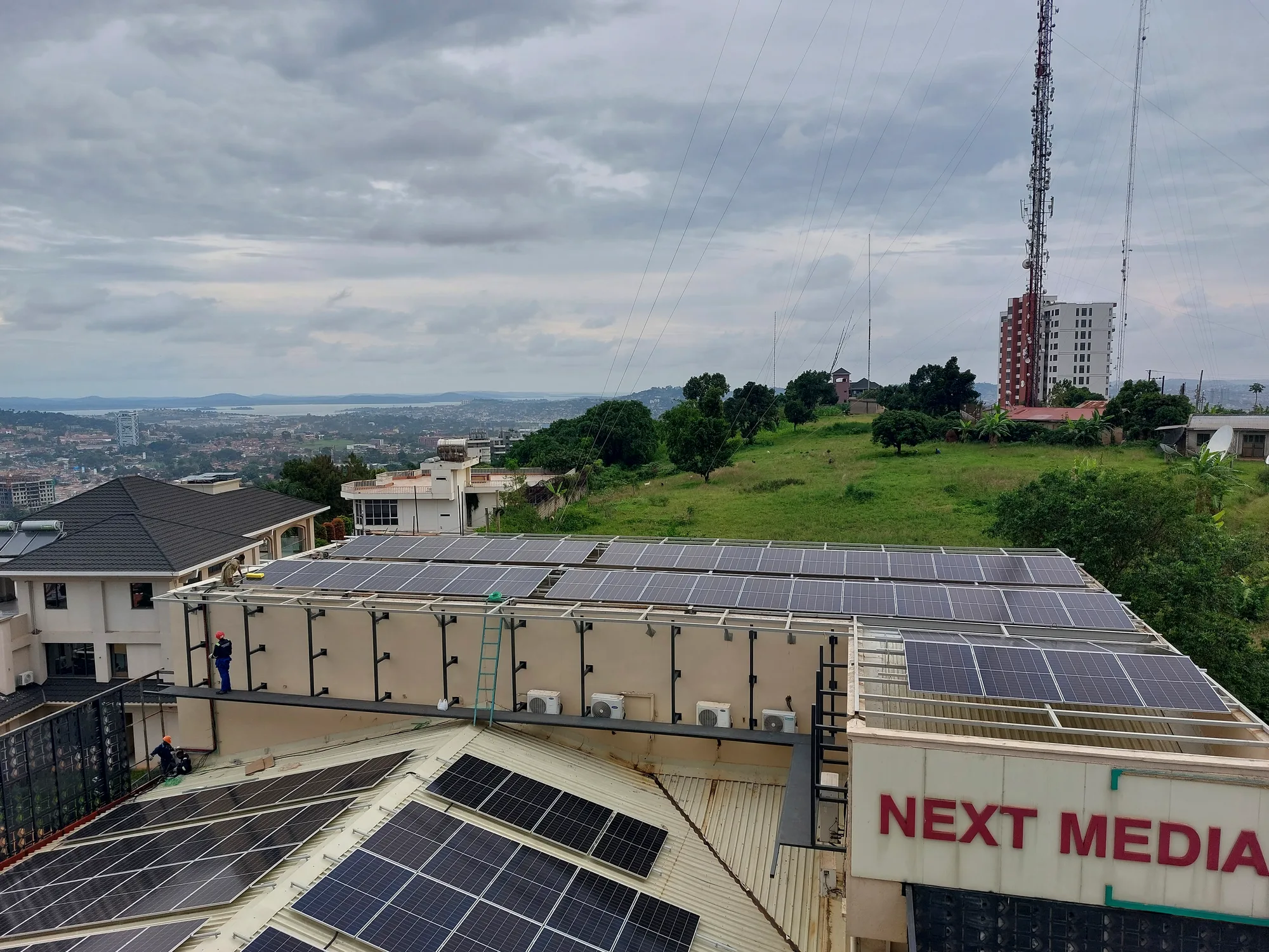 Rooftop solar array on a hillside building overlooking a city skyline