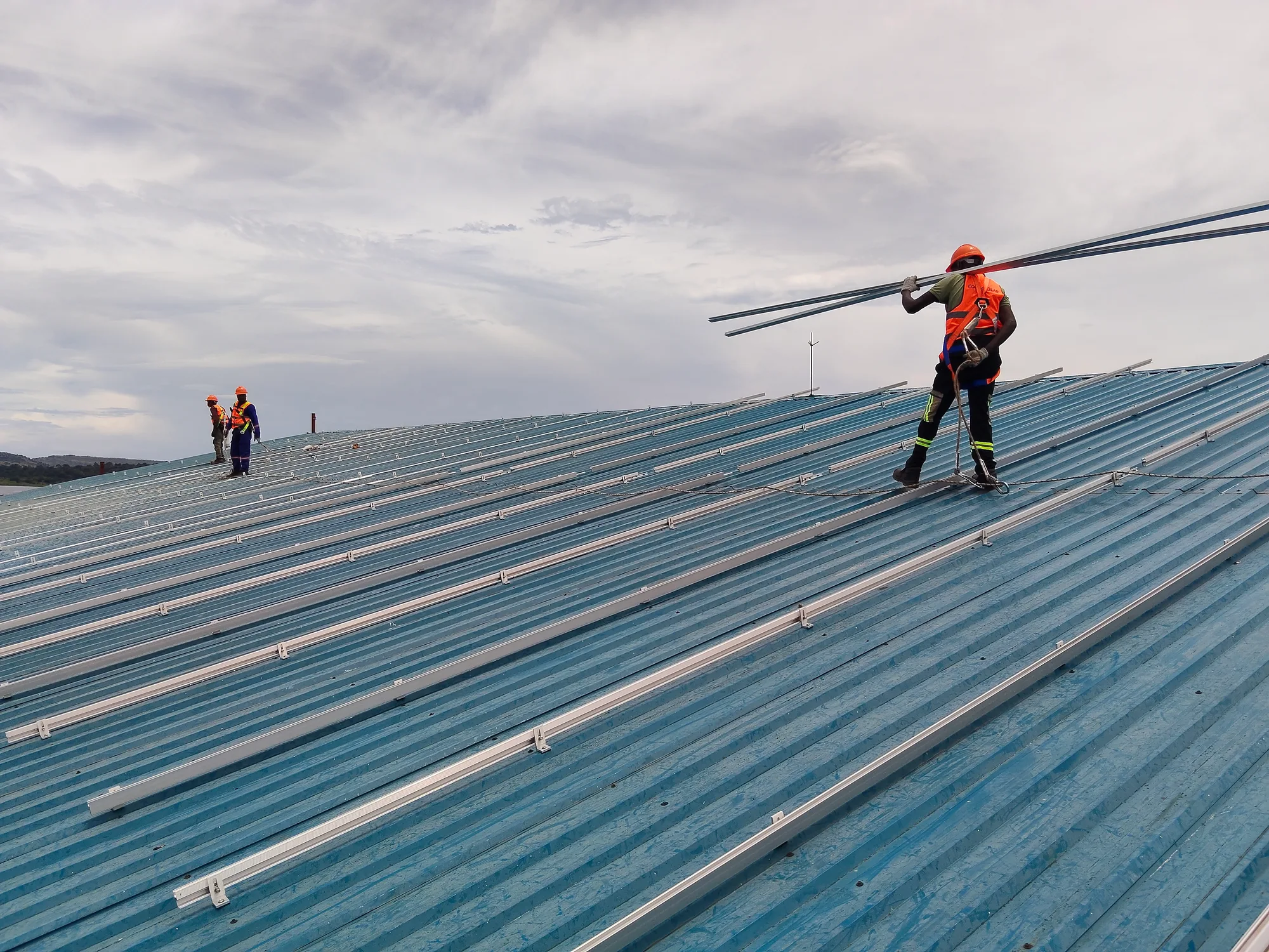 Solar panel mounting rails being installed on a large industrial rooftop