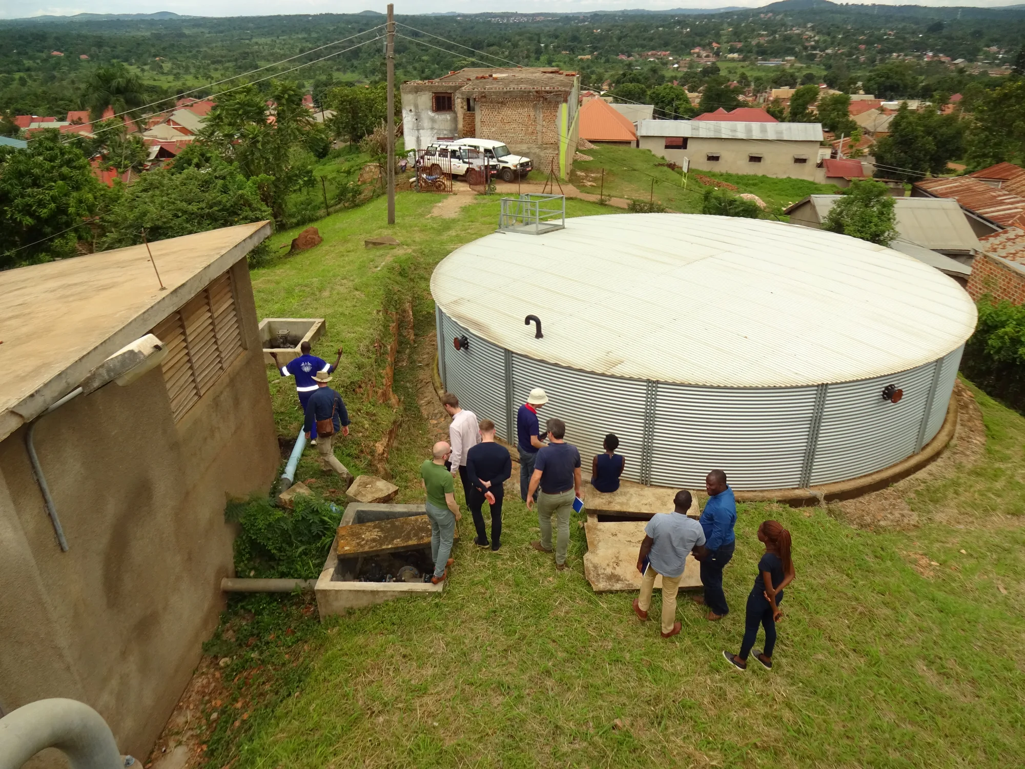 A group of engineers inspecting a large water storage tank on a hillside